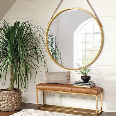Round hanging mirror with gold frame above bench in modern living room home decor Qatar