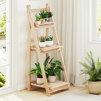 Wooden indoor plant stand holding multiple plants near window allowing sunlight exposure in Qatar